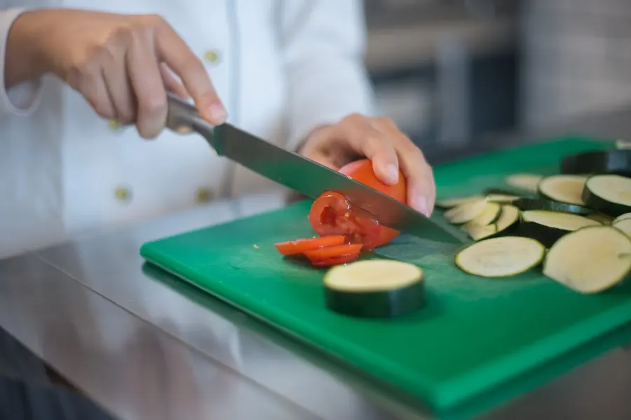 Chef qui découpe des légumes en cuisine